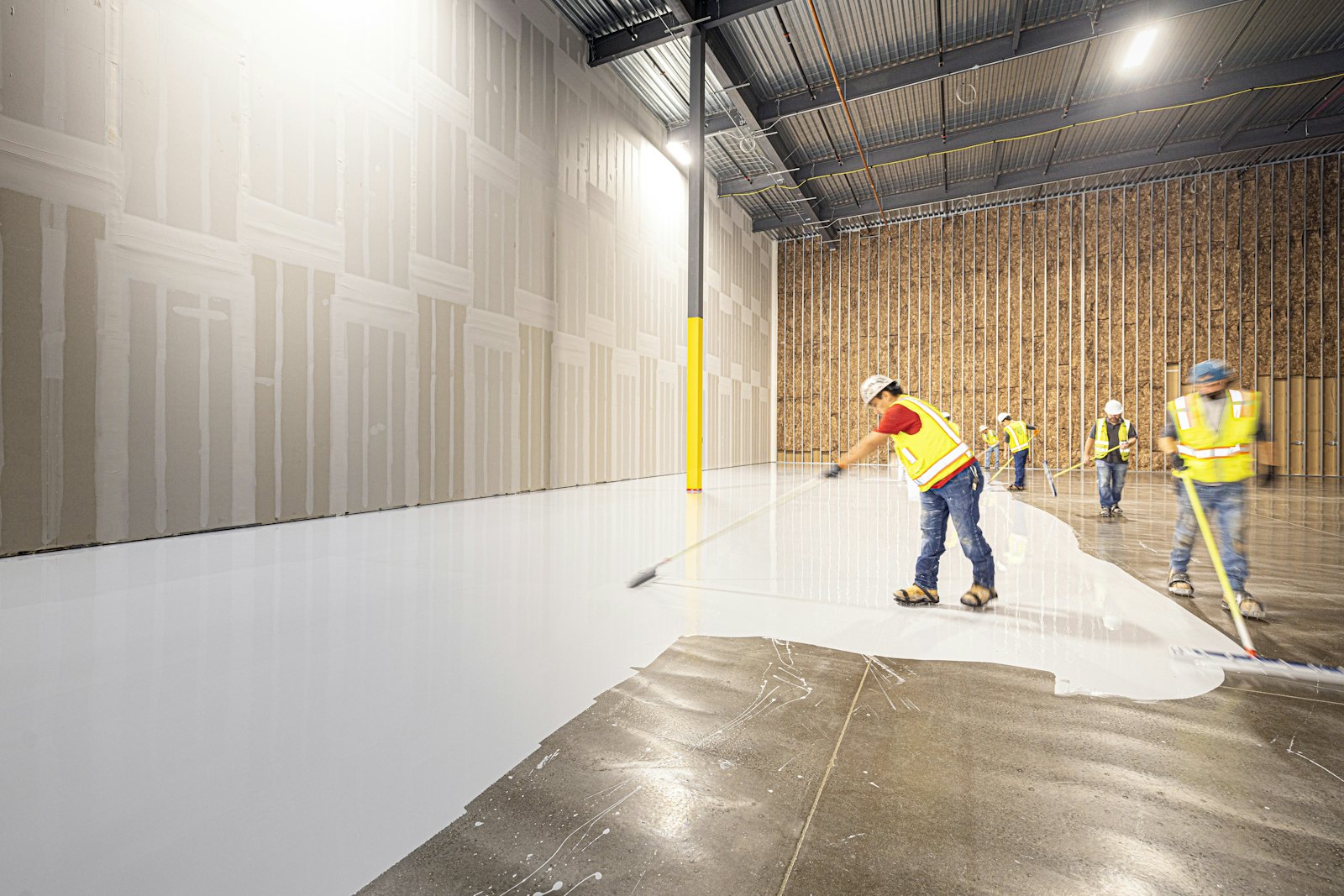 Workers coating a large concrete floor